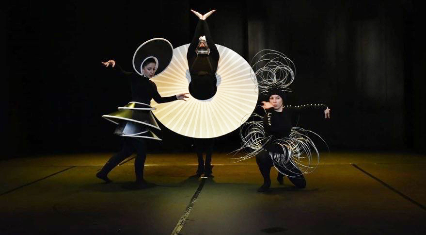 three dancers in reproductions of Oskar Schlemmer costumes in black, white and silver