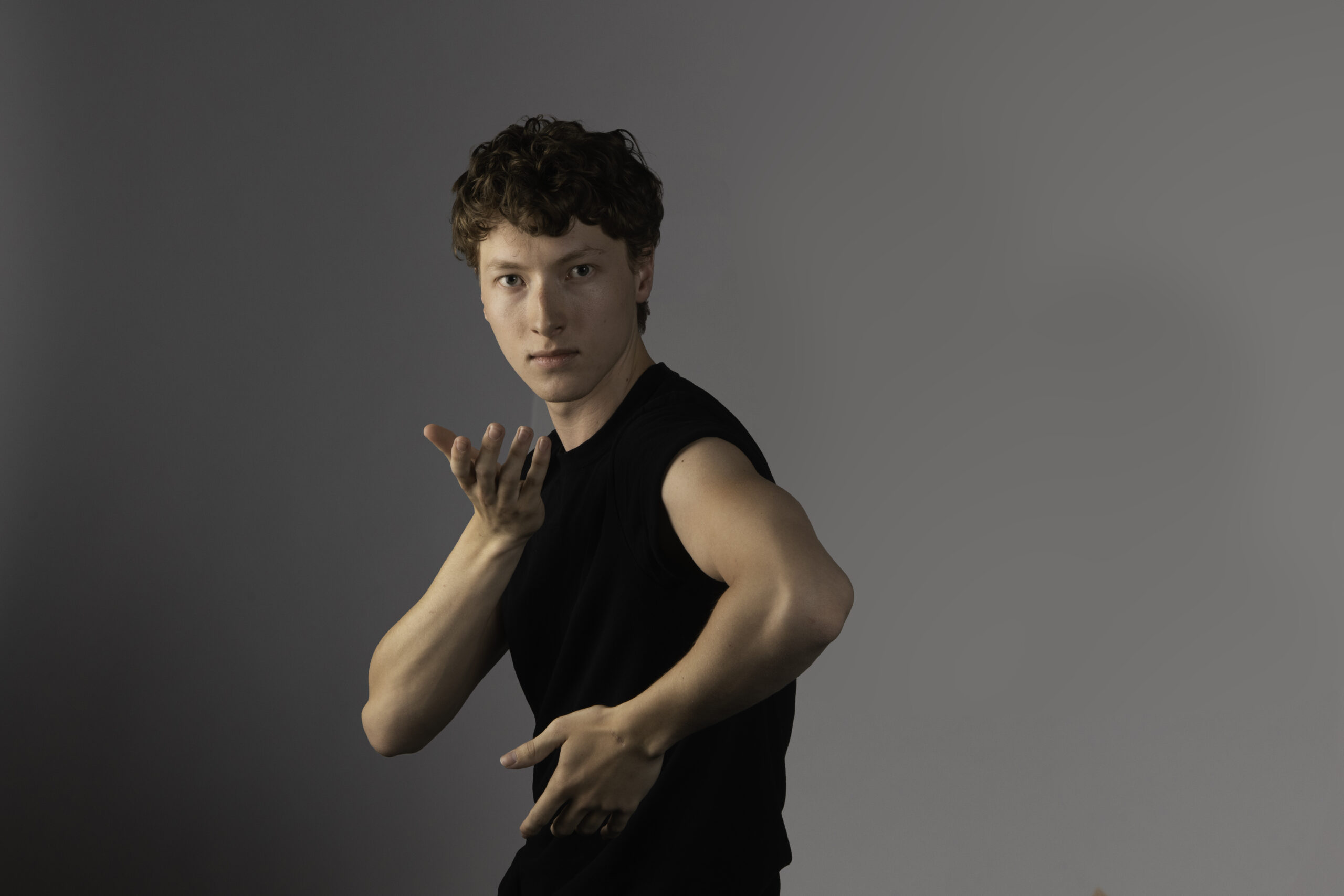 Male Dancer with short curly brown hair in short sleeved black t-shirt